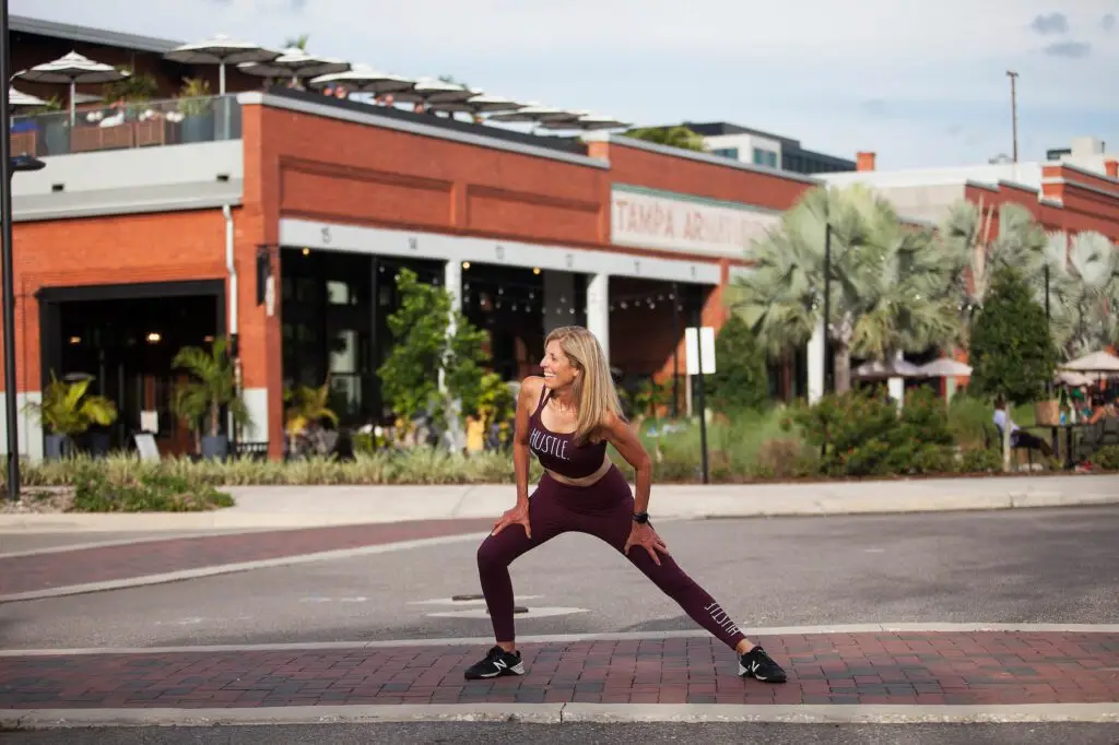 Woman stretching outdoors near brick building