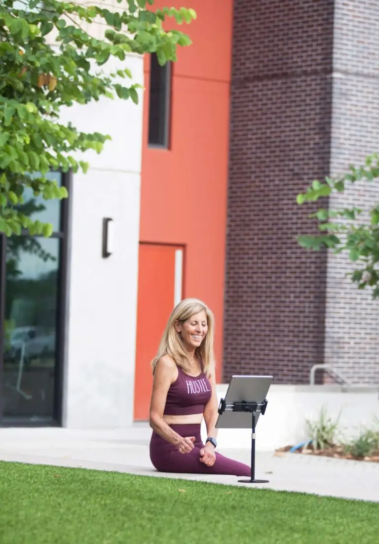 Woman doing outdoor exercise with tablet, green background.
