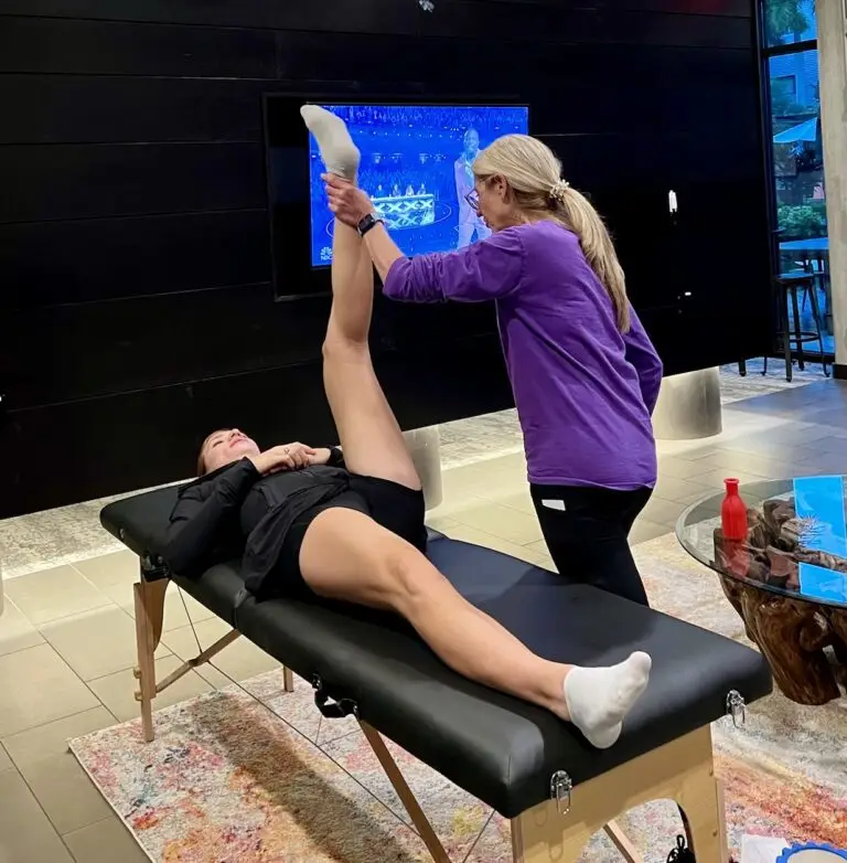 Person receiving leg stretch on massage table.